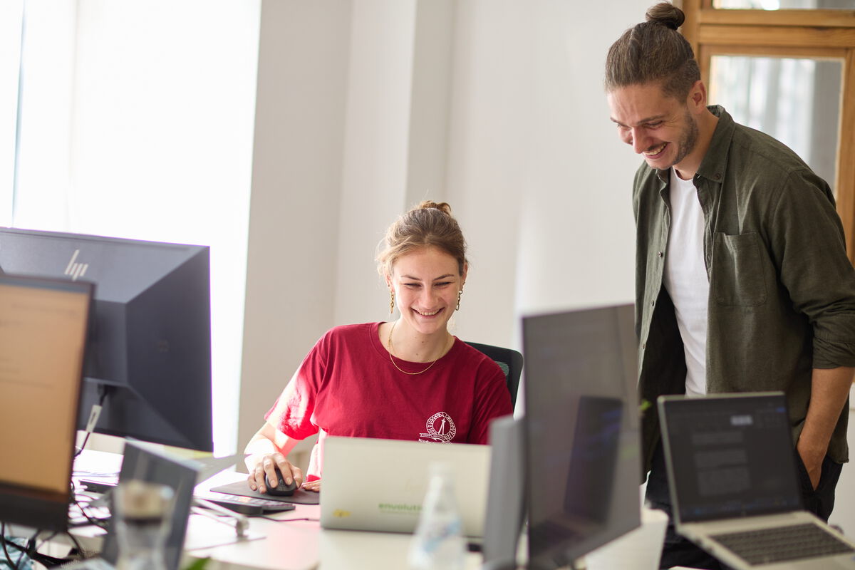 Besprechung von zwei Mitarbeiter an einem Desktop PC im Büro